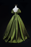 Green ball gown on a mannequin against a black background