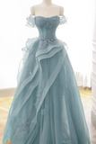 Light blue off-shoulder gown with floral details on a mannequin against a neutral background.