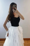 Person wearing a black top and white tulle skirt taking a mirror selfie.