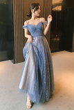 Woman in a blue off-shoulder dress standing indoors.