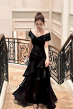 Woman in a black evening gown standing on a staircase.