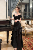 Woman in a black evening gown standing in a formal room with a piano and elegant decor.