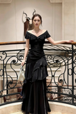 Woman in a black evening gown standing on a staircase with decorative railings.
