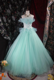 Mint green evening gown on a mannequin against a floral curtain backdrop