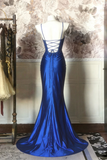 Blue evening gown on a mannequin against a decorative wall.