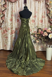 Green evening gown on a mannequin with floral decorations in the background