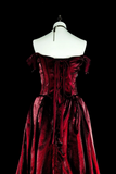 Red velvet evening gown on a mannequin against a black background