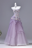 Purple evening gown with floral embellishments on a mannequin against a gray background