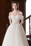 Woman wearing a white wedding dress with floral details in an elegant setting.