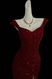 Red sequin dress on a mannequin with a necklace against a black background
