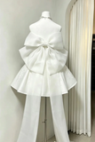 White strapless dress with a large bow on a mannequin against a neutral background