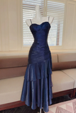 Blue evening gown on a mannequin in front of a window with blinds.