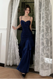 Woman in a blue evening gown standing in a room with lace curtains.