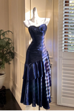 Navy blue evening gown on a mannequin against a neutral wall.