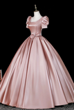Pink satin gown on a mannequin against a black background