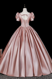 Pink satin ball gown on a mannequin against a black background