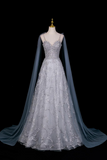 Elegant silver evening gown with a long train on a mannequin against a black background