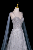 Silver beaded evening gown with a cape on a mannequin against a black background