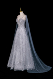 Elegant silver evening gown with a long train on a mannequin against a black background