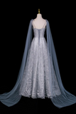 Elegant silver evening gown with a long train on a mannequin against a black background