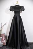 Black evening gown on a mannequin against a white wall.