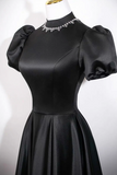 Black dress with puffed sleeves on a mannequin against a white background