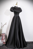 Black evening gown on a mannequin against a plain background