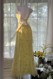 Yellow dress on a mannequin in front of a window with a view of trees.