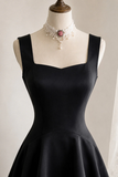 A black sleeveless fit-and-flare dress displayed on a mannequin torso, styled with a pearl choker necklace featuring a pink gemstone, against a plain light background.