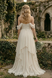 Woman in a white dress standing in an outdoor setting with stone ruins and greenery.