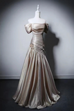 A champagne-colored off-the-shoulder evening gown displayed on a white mannequin against a dark gray studio background.