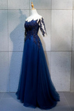 A floor-length navy blue tulle evening gown displayed on a mannequin against a light gray tiled wall. The dress features a sweetheart neckline, lace-embellished bodice, and sheer lace sleeves.