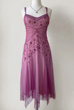 A mauve purple tulle midi dress with floral applique and a ruffled sweetheart neckline, displayed on a white mannequin torso against a plain off-white wall.