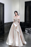 Woman in a white evening gown standing in a room with black doors and a marble piece.