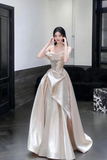 Woman in a white evening gown standing in a room with a neutral background