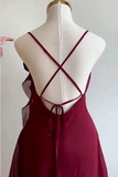 A burgundy slip dress displayed on a cream dress form, showing the back view with thin crisscross straps and a tie closure.