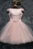 A light pink off-the-shoulder tulle dress with a lace bodice and a short flared skirt, displayed on a wooden hanger against a dark textured background.