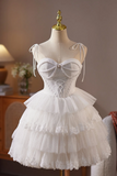 A white lace and tulle short dress displayed on a cream mannequin with a gold top. The dress features a sweetheart neckline, a lace-up corset bodice, and a tiered ruffled skirt.