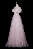 A light pink off-the-shoulder tulle ball gown displayed on a mannequin against a solid black background.