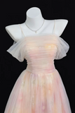 A pastel pink and peach tulle formal dress displayed on a white mannequin against a black background, with sheer flutter sleeves, thin straps, and a delicate silver necklace.