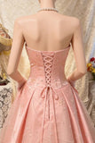 Pink strapless dress with intricate back design on a neutral background