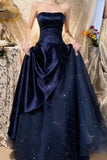 Navy blue strapless gown with a large skirt in front of a decorative background