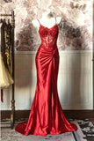Red evening gown on a mannequin against a decorative wall.