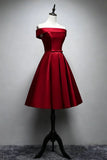 A red off-the-shoulder short dress with a flared skirt and waist bow, displayed on a mannequin torso against a gray wall.