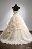 An ivory ball gown wedding dress displayed on a black mannequin against a neutral gray studio background. The dress features a structured corset bodice with thin straps, a full layered tulle skirt, and large dimensional fabric roses across the front.