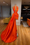 Orange evening gown on a mannequin in a room with furniture and decor.