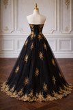 Black evening gown with gold embroidery on a mannequin against a decorative wall.