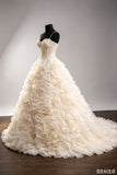 An ivory wedding gown with a strapless lace bodice and a voluminous skirt made of layered fabric roses, displayed on a black dress form against a neutral studio background.